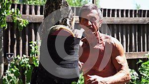 Older sportsman exercising martial arts at summer day. An adult male athlete showing fighting techniques on a wooden