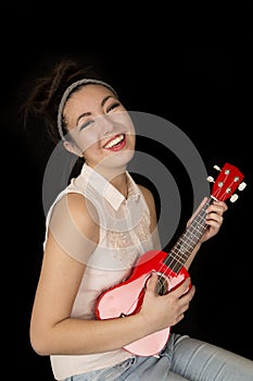 Older teen girl playing ukulele sitting and smiling