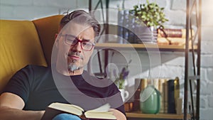 Older white man in glasses reading at home