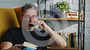 Older white man in glasses reading at home