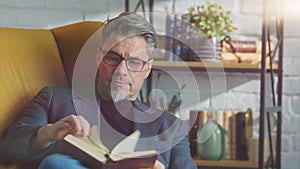 Older white man in glasses reading at home