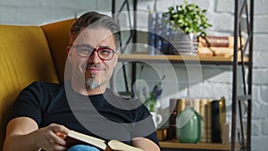 Older white man in glasses reading at home