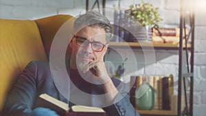 Older white man in glasses reading at home