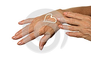Older woman applying cream on hands close-up on white