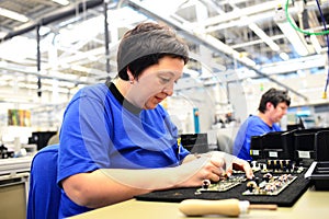 older woman assembles electronic components in a hi tech factory photo
