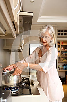 Older woman boiling water on kitchen stove top