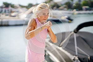 Older woman doing shadow boxing outdoors. Senior female doing sport in a coastal port