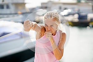 Older woman doing shadow boxing outdoors. Senior female doing sport in a coastal port