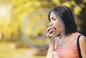 Older woman is eating apple after exercising to take care of the