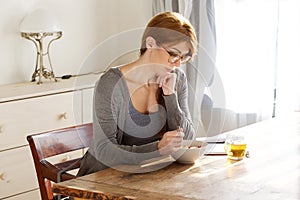 Older woman having breakfast and reading book in morning