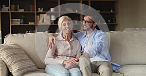 Older woman her adult son enjoy talk sit on sofa