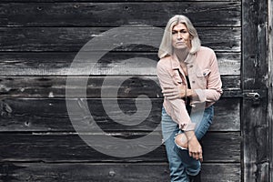 Older woman in her fifties in front of an old wooden wall.