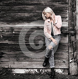 Older woman in her fifties in front of an old wooden wall.