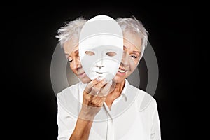 Older woman hiding happy and sad face behind mask