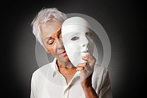 Older woman hiding sad face behind mask