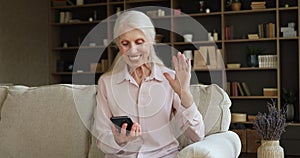Older woman holds cellphone make videoconference call
