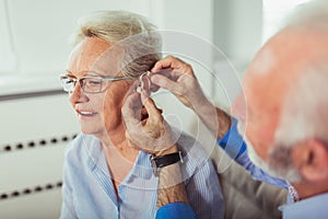 Older woman and man or pensioners with a hearing problem photo