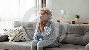 Older woman praying with hope at home, holding hands together