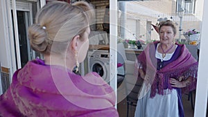 Older woman putting on earrings and looking at herself in mirror