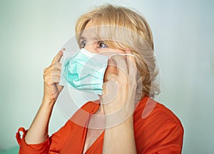 Older woman putting on surgical mask correctly