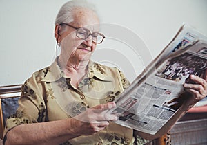 Older woman relaxing and reading newspaper