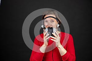 Older woman with a set of retro corded headphones in a red sweater dancing and enjoying music