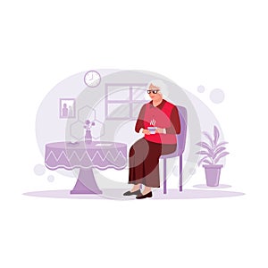 The older woman sits relaxed on a chair at home, drinking warm tea.