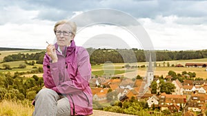 Older woman sitting on bench and smoking