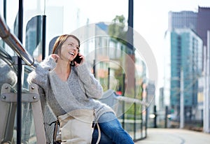 Older woman sitting outside in the city talking on mobile phone