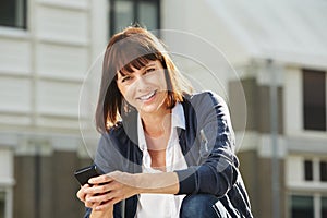 Older woman sitting outside with smart phone in city
