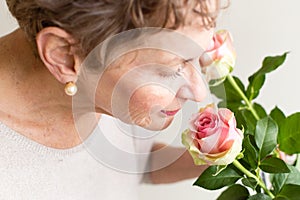 Older woman smelling roses