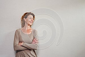 Older woman standing with arms crossed looking away smiling