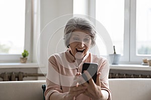 Older woman staring at cell phone screen with opened mouth