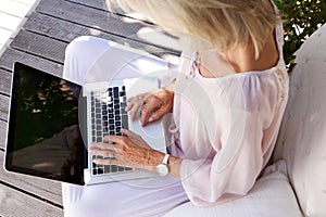 Older woman typing on laptop keyboard