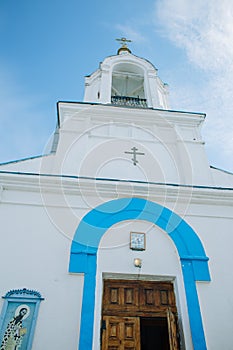 The oldest Church is blue and white with a Golden dome and cross. Above the Church is a blue sky