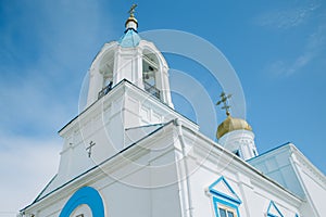 The oldest Church is blue and white with a Golden dome and cross. Above the Church is a blue sky