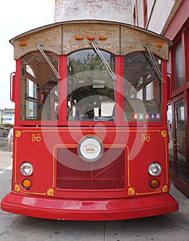 Oldfashioned red trolley bus front on.