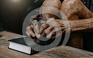 Oldman sitting and studying the scriptures.The  wooden cross in the hands. Christian education concepts The Holy Scriptures open