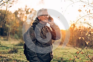 Oldman using smartphone in forest