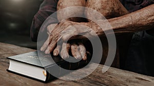 Oldmans hands together in prayer to God along with the bible In the Christian concept and religion, woman pray in the Bible