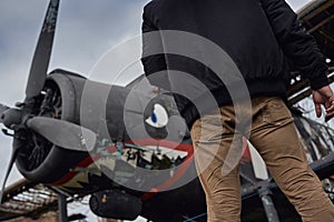 Oldschool pilot in the bomber jacket posing near the aircraft