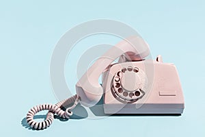 Oldschool pink telephone on a blue background