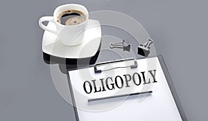 OLIGOPOLY text on paper sheet with coffee on the black background