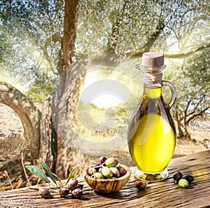 Olive berries in the wooden bowl and bottle of olive oil on the