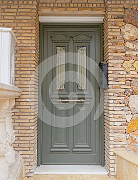 Olive green door on bricks and stone wall house entrance