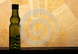 Olive green glass bottle filled glass marble Spheres on antique paper background
