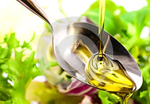 Olive oil being poured into a spoon and salad