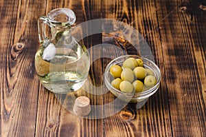 Olive oil in a bottle and fruits of olives in a bowl.