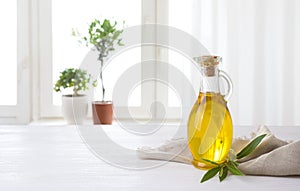 Olive oil bottle on table against sunlit kitchen window background