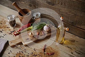 Olive oil in a bottle on a wooden background with a wooden board with spice and herbs for decoration